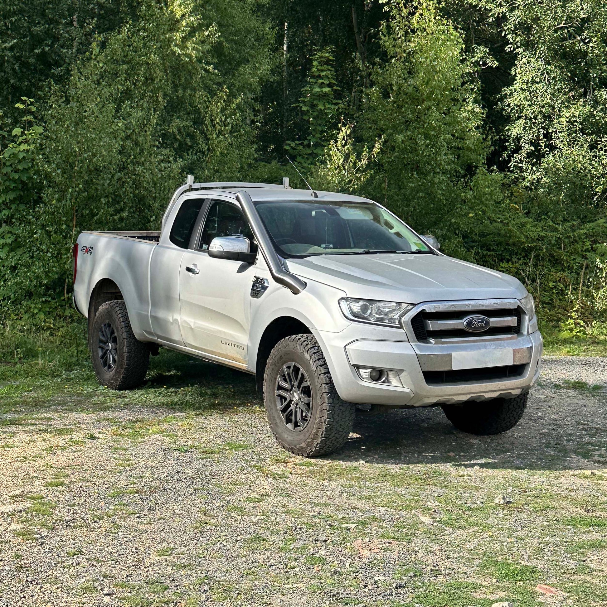 Silver Ford pickup truck parked on a gravel path with trees in the background