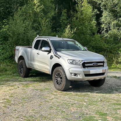 Silver Ford pickup truck parked on a gravel path with trees in the background