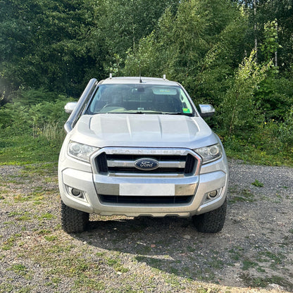 Silver Ford truck parked on a gravel area with trees in the background